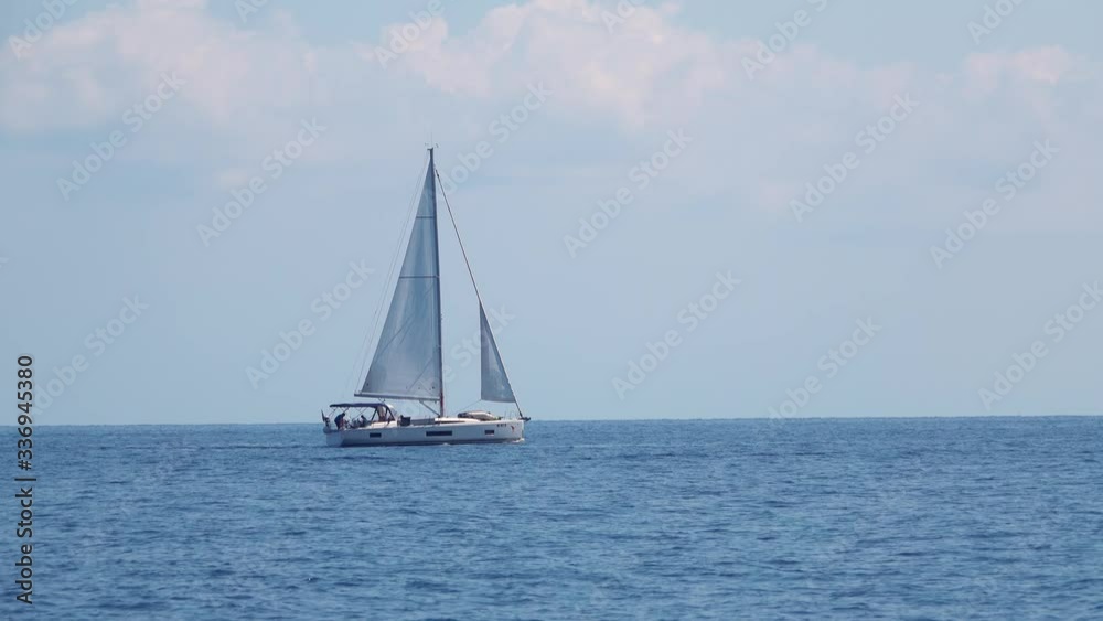 White sailing boat with people on board. Floating across Mediterranean sea. Lipari Islands. Sicily, Italy. Horizon, blue sky White sailing boat with people on board. Floating across Mediterranean sea. Lipari Islands. Sicily, Italy. Horizon, blue sky