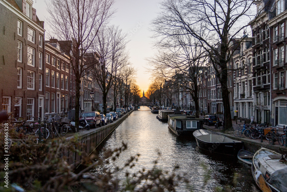 One of the water channels in Amsterdam, with a church on the background under the sunset