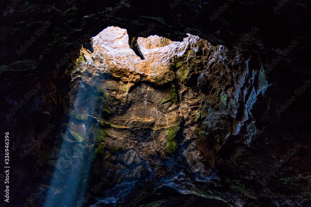 Detail of a sunray coming into a rock cave through a hole in the ceiling. Lanzarote, Canary Islands, Spain Detail of a sunray coming into a rock cave through a hole in the ceiling. Lanzarote, Canary Islands, Spain