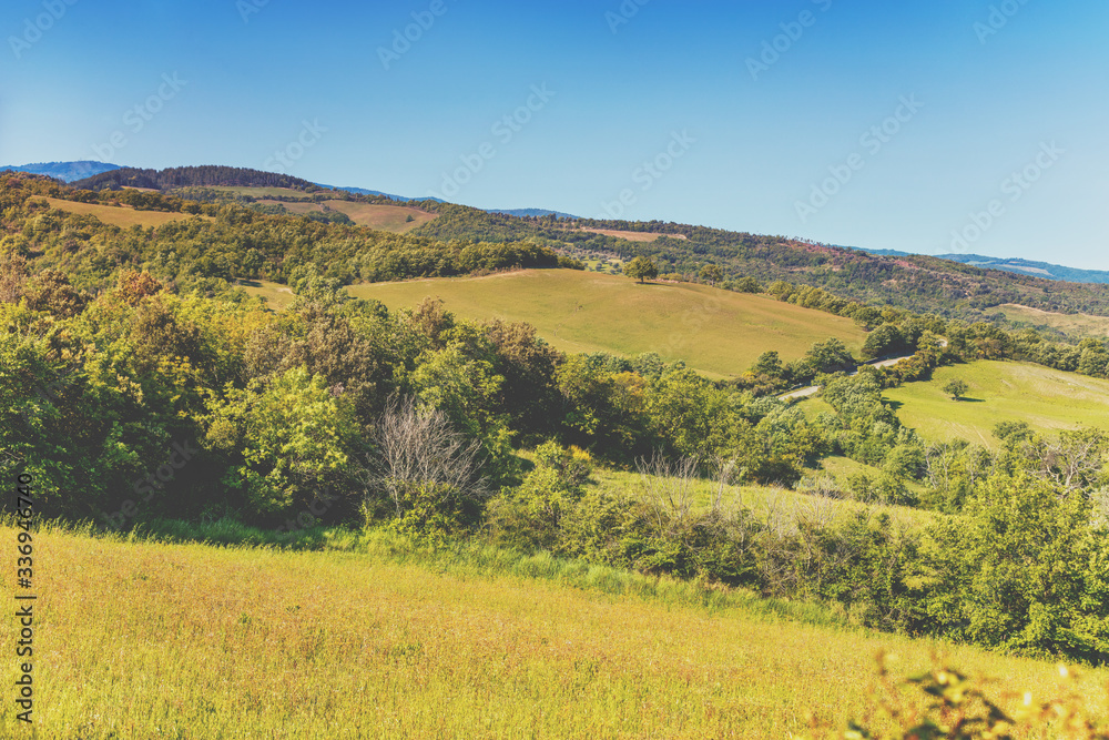 Beautiful spring landscape. Landscape with mountains and valley on a sunny day. View from above of sunny fields on rolling hills in Tuscany, Italy