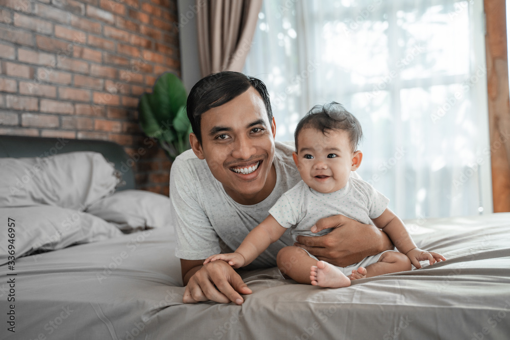 father bonding with baby. man playing with his daughter on the bed father bonding with baby. man playing with his daughter on the bed