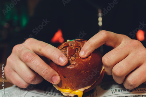 A bitten fresh burger in the hands of a man. photo