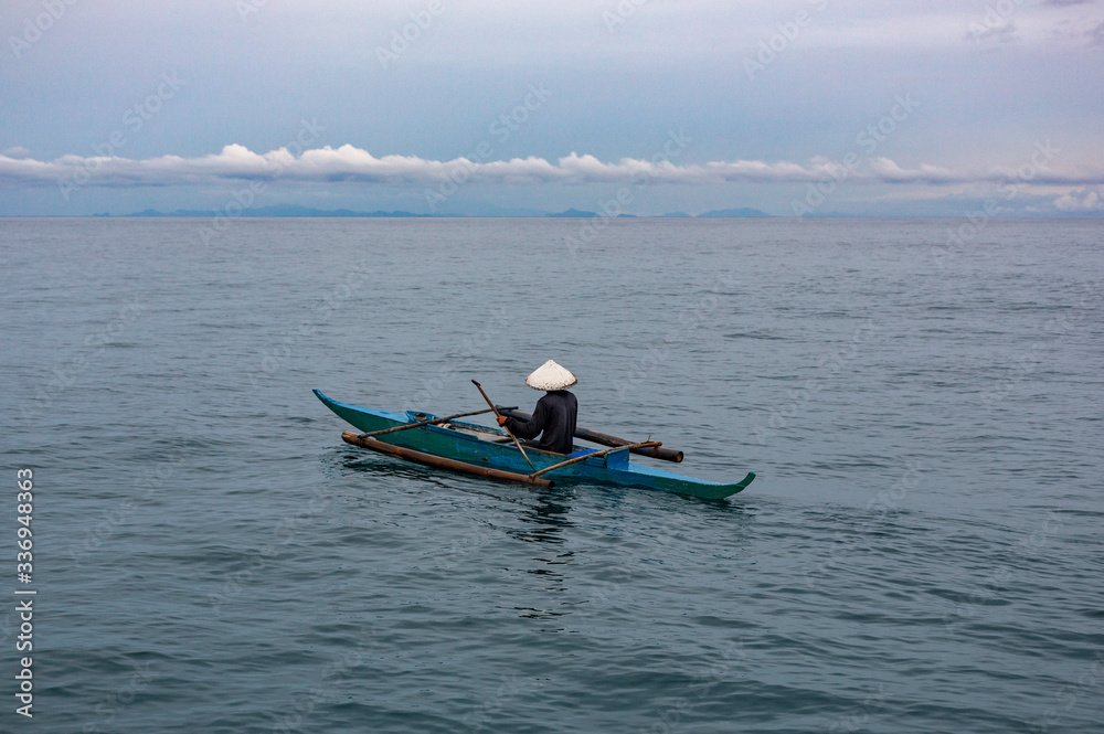 A philippine man with a white hat on a boat in the middle of the ocean in Coron Island, Philippines