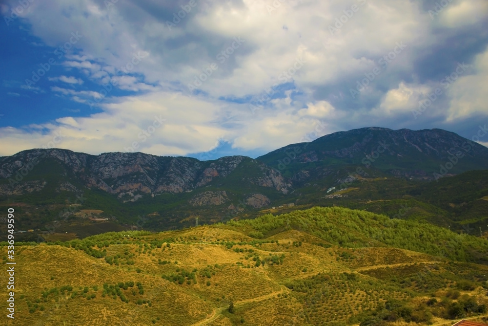 Fototapeta premium Mountains under the sun and fluffy white clouds in summer