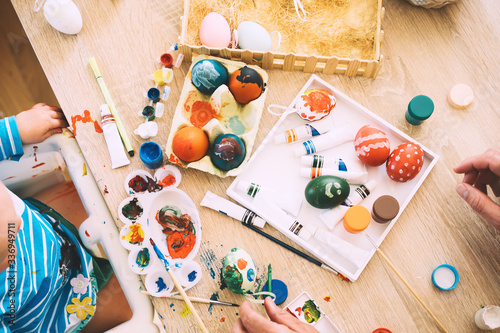 Children painting eggs. Family preparing for Easter.