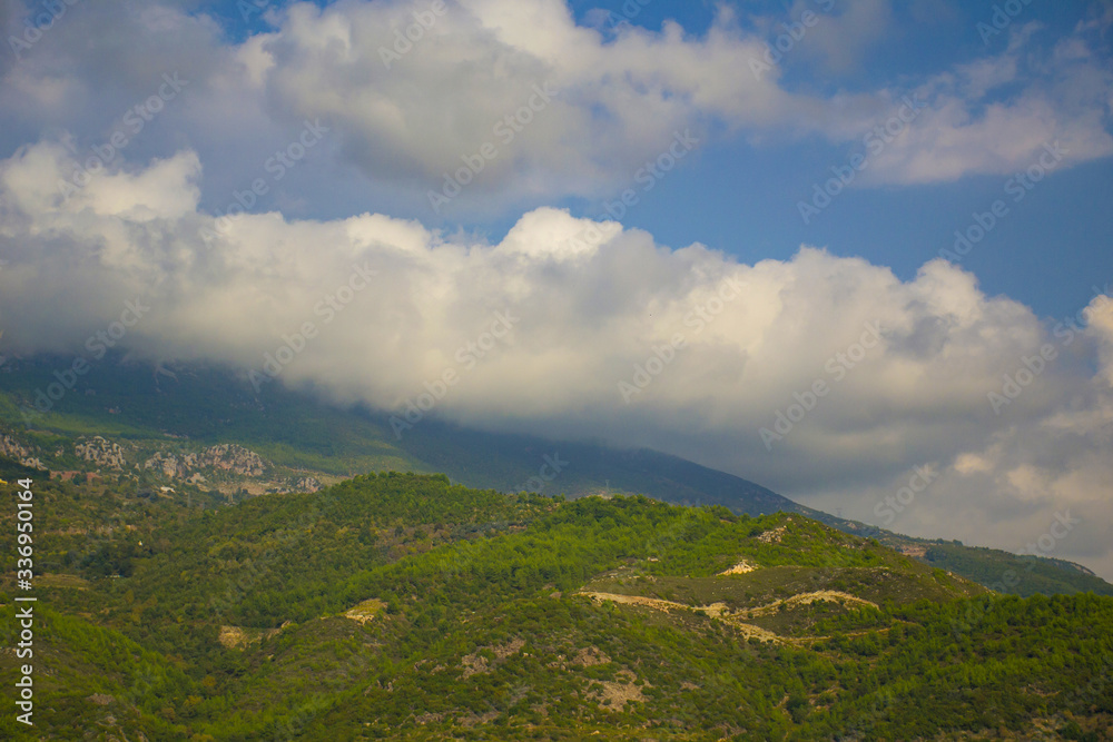 Mountains under the sun and fluffy white clouds in summer