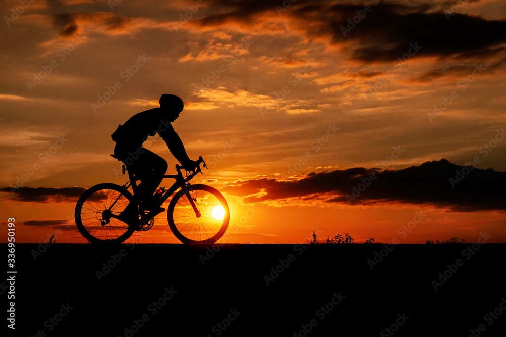 Silhouette of the cyclist riding a road bike at sunset.