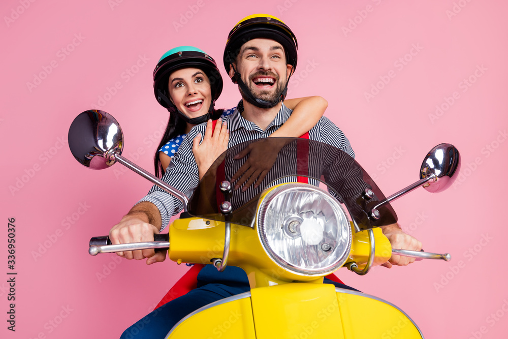 Low below angle view portrait of his he her she nice attractive dreamy cheerful cheery couple driving moped having fun journey isolated over pink pastel color background