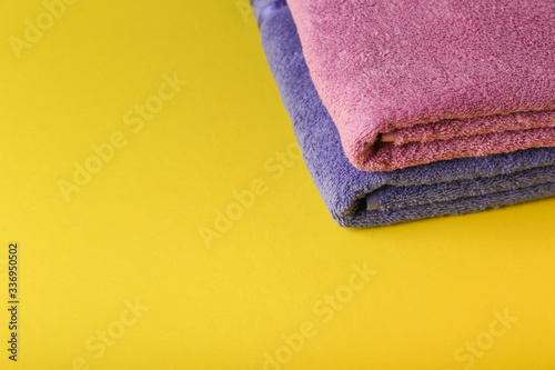 folded clean towels on yellow background with copy space