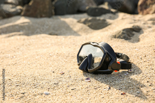 black diving mask on the sand. diving mask on the beach next to the rocks