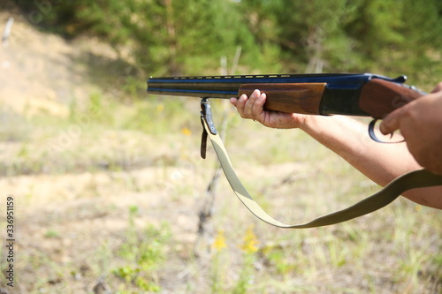 hunter's hands hold a hunting rifle in forest close up. aiming in the target