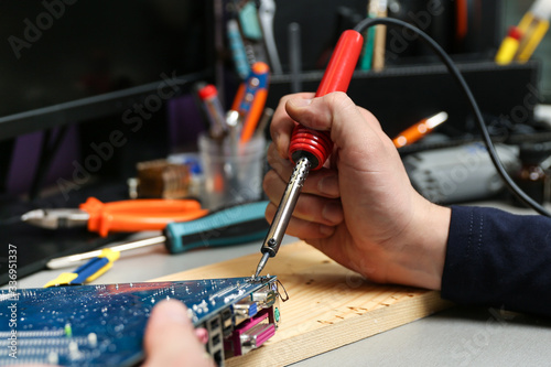 worker's hands solder with soldering iron in the workshop close up