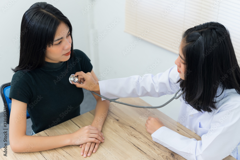 Young Asian female doctor uses the stethoscope to examine and diagnose adult female patient’s sickness and symptom. Medicine and health care concept. Doctor and patient.