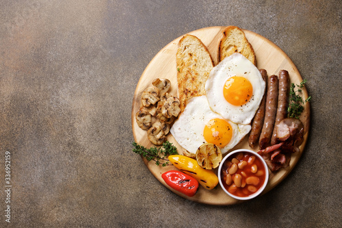 English breakfast on cutting board. Bacon, Bean Tomato Sauce, Grilled Tomatoes, Champignon Mushrooms and Fried Eggs