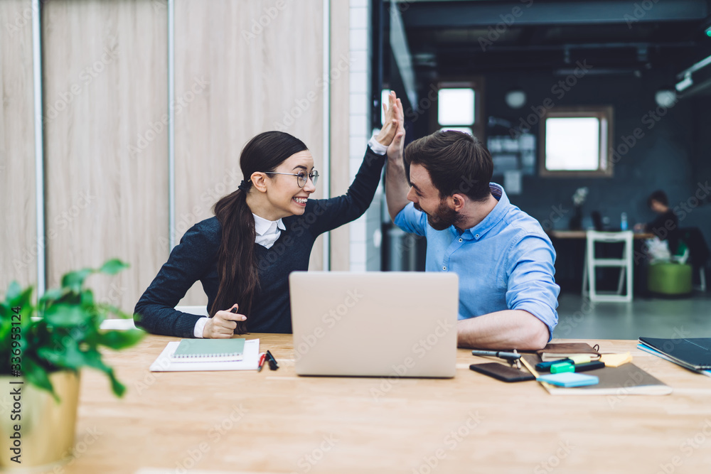 Joyful woman giving high five to bearded man in office Joyful woman giving high five to bearded man in office