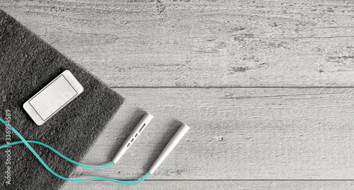 Skipping rope and yoga mat on a wooden floor background. Fitness lifestyle concept. Smartphone for accounting workout. Top view, copy space for text.
