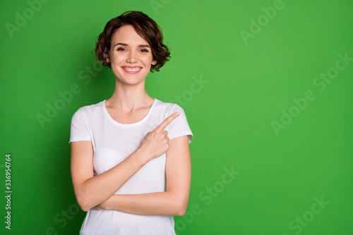 Photo of attractive lady wavy hairdo direct finger side empty space demonstrating cool shopping novelty low price wear casual white t-shirt isolated green color background