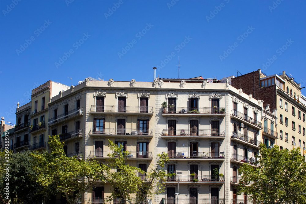 View of traditional, historical, typical residential buildings in Barcelona showing Spanish / Catalan architectural style. It is a sunny summer day.