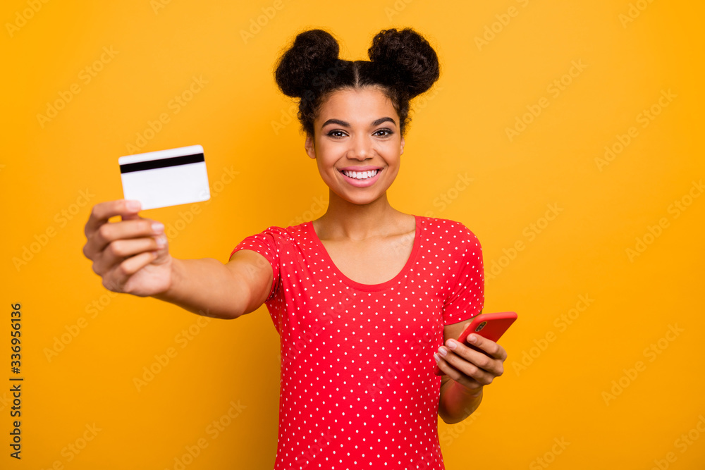 Easy banking transferring. Positive afro american girl hipster hold plastic card cell phone recommend pay online modern technology wear red dotted t-shirt isolated bright shine color background Easy banking transferring. Positive afro american girl hipster hold plastic card cell phone recommend pay online modern technology wear red dotted t-shirt isolated bright shine color background