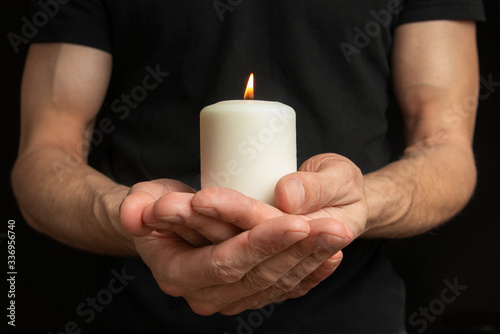 close view of a big white candle in male hands