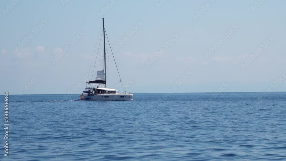 White sailing boat with people on board floating across Mediterranean sea. Lipari Islands. Sicily, Italy. Horizon, blue sky White sailing boat with people on board floating across Mediterranean sea. Lipari Islands. Sicily, Italy. Horizon, blue sky