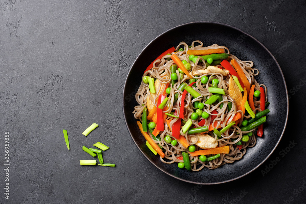 Stir fry noodles with vegetables and soy sauce. Asian food background. Black stone background