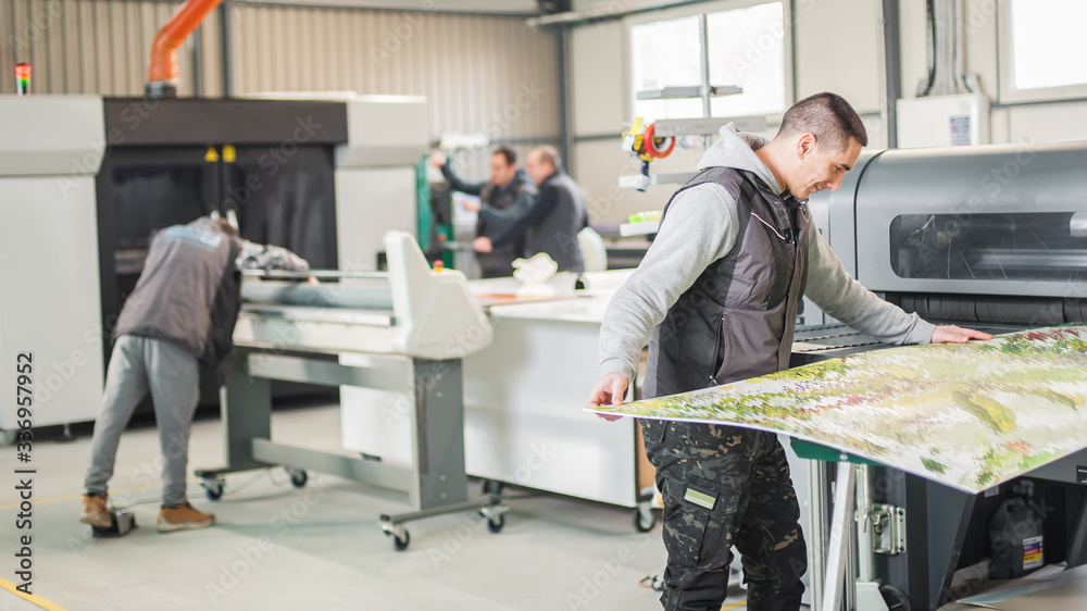 © guruXOX - Large group of technicians works in printing printshop press hall