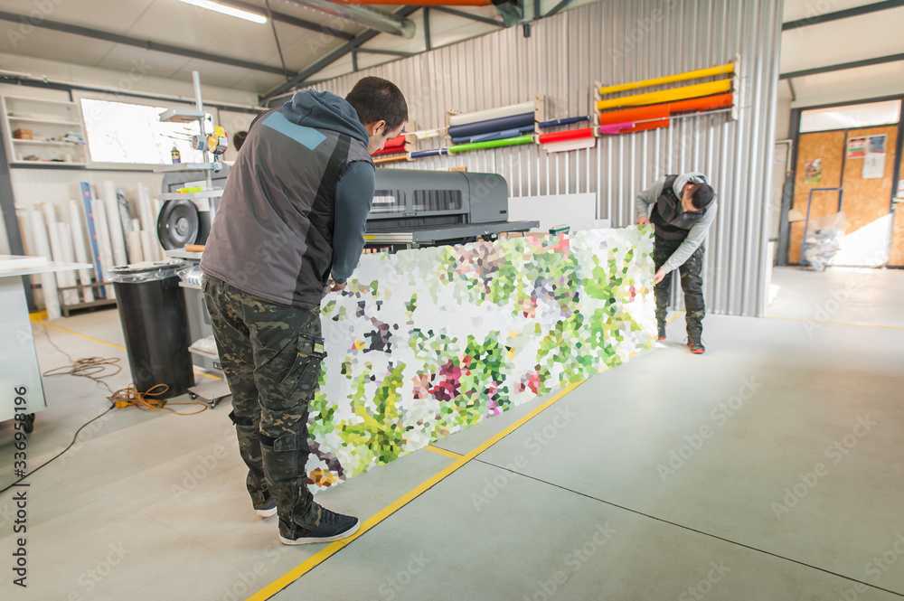 Obraz premium Technicians works in large printing press hall and printshop office