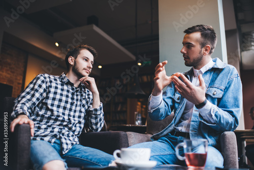 Serious adult males friends talking together in cafe