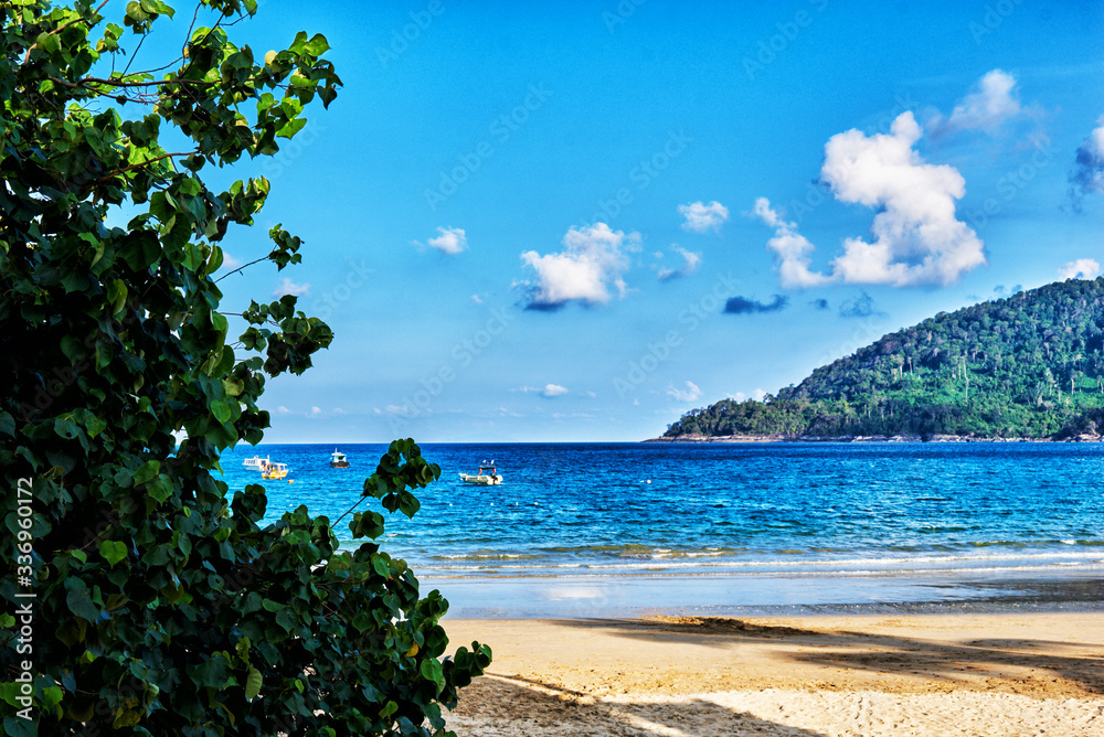 View of beautiful crystal clear water and gold beach with boats in summer of tropical island in in Malaysia. Travel, adventure, summer vacation.