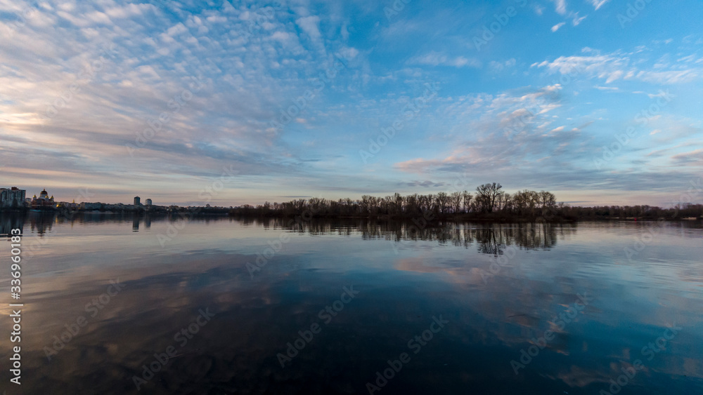 Sunset in the sky over the water surface on the background of the city and nature Ukraine Kiev 2020