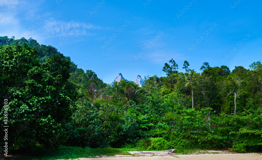 Tioman tropical island in Malaysia. South China sea. Southeast Asia. Tioman Island with Mukut Dragon Horn in the background. Tropical paradise. Summer, holiday, outdoor vacation trip concept.
