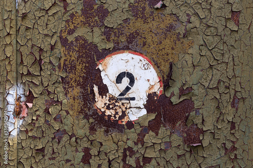 rusty metal texture with old peeling paint and the number 2 on a white background in a red circle