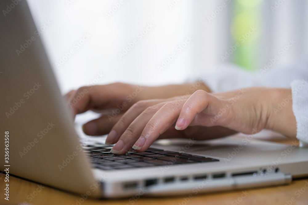 Cropped shot of a woman using a laptop while working from home Cropped shot of a woman using a laptop while working from home