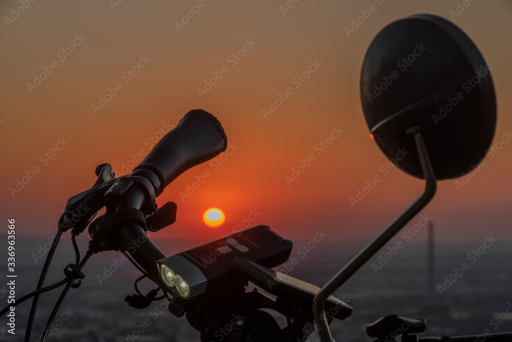 Handlebar mirror and light on electric bike in sunset color evening