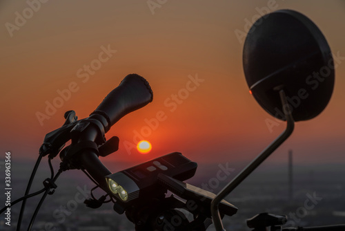 Handlebar mirror and light on electric bike in sunset color evening