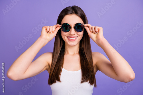 Photo of attractive pretty cool stylish lady hold retro vintage sun specs arms good mood wear white singlet isolated pastel purple color background