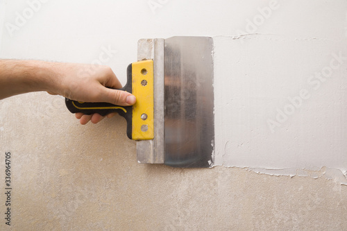 Photos Worker hands using spatula and plastering old cement wall with putty