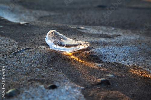 The shining piece of ice on icy sand