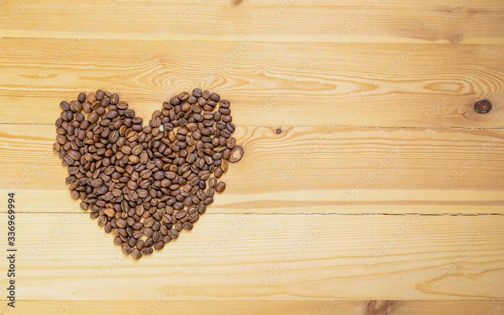 Roasted coffee beans shaped like hearts on a wooden table