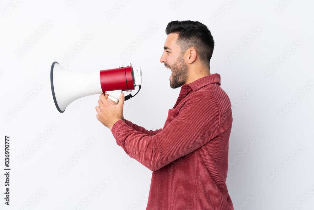 Young handsome man with beard wearing a corduroy jacket over isolated white background shouting through a megaphone Young handsome man with beard wearing a corduroy jacket over isolated white background shouting through a megaphone