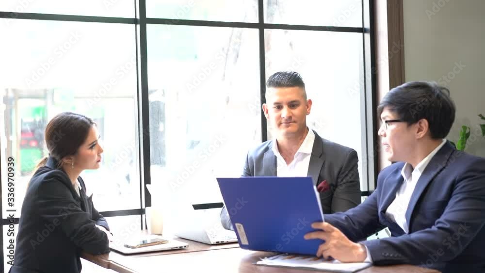 Co-working space concept. Asian business looking in front of laptop while sitting at co-working space. The young manager is encouraging and appreciating his colleagues. Co-working space concept. Asian business looking in front of laptop while sitting at co-working space. The young manager is encouraging and appreciating his colleagues.