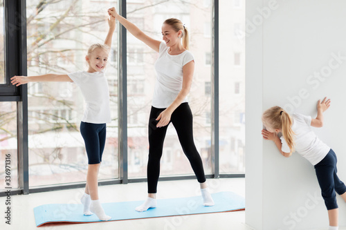 Mother working out with daughters at home on yoga mat