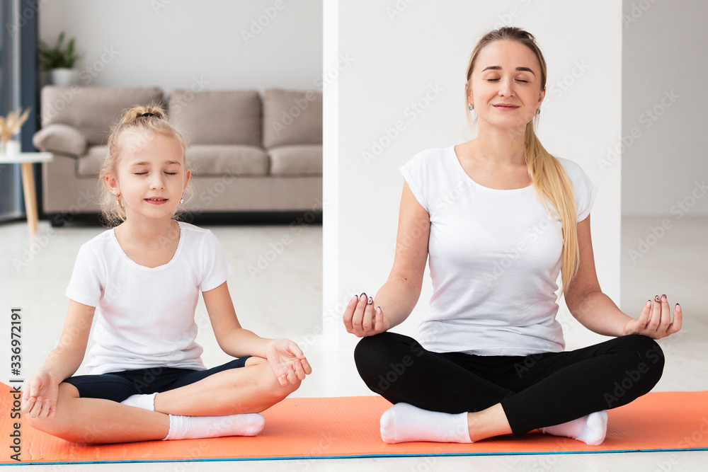 Front view of mother doing yoga with daughter at home Front view of mother doing yoga with daughter at home