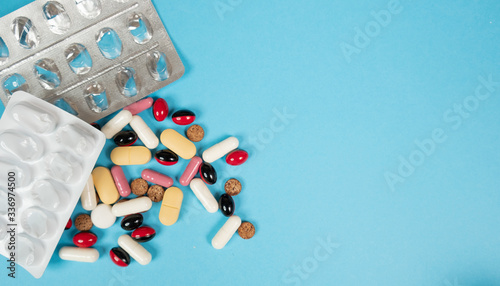 Various medications, tablets, and vitamins. Blue background, place to insert text. Health and pharmacy.