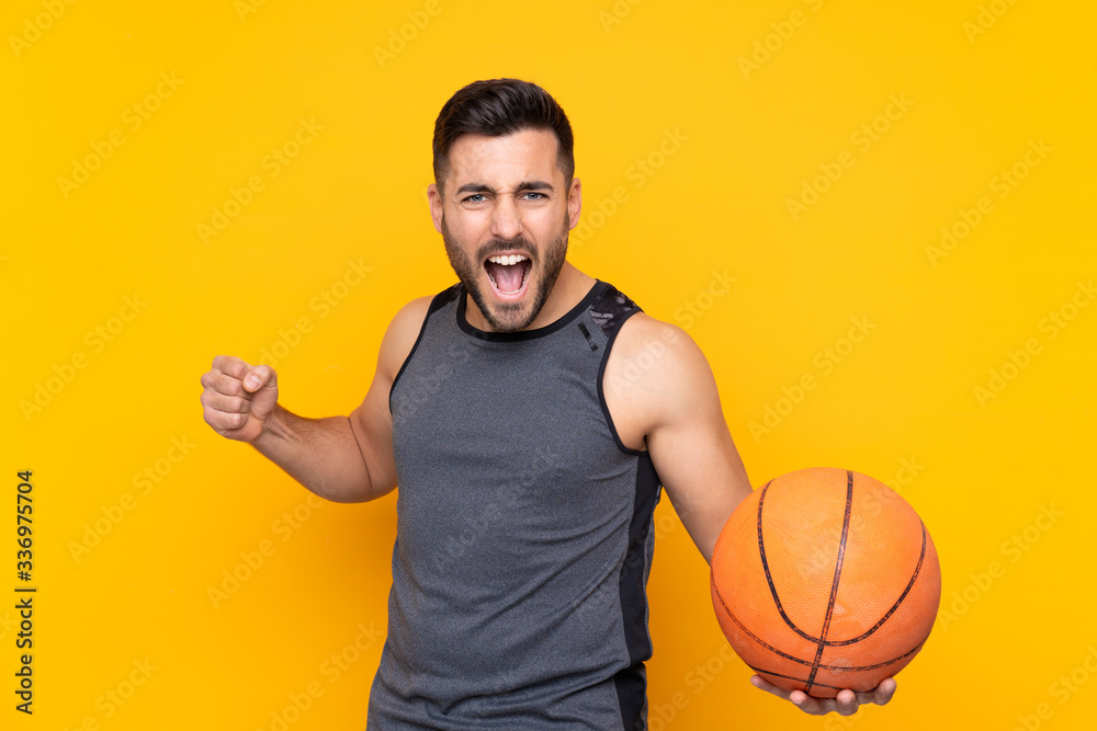 Man over isolated yellow background playing basketball Man over isolated yellow background playing basketball