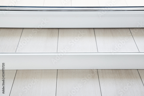 The floor is made of ceramic tiles, granite. Imitation of a wooden board. Connection of a floor with a threshold of a balcony. A white MDF skirting board is adjacent to the threshold. © lial88