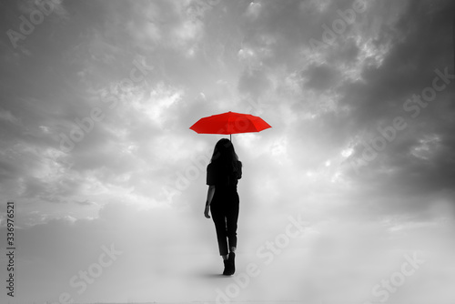 Silhouette of girl with umbrella in a dreamlike context - red umbrella with leaden sky - color contrast.