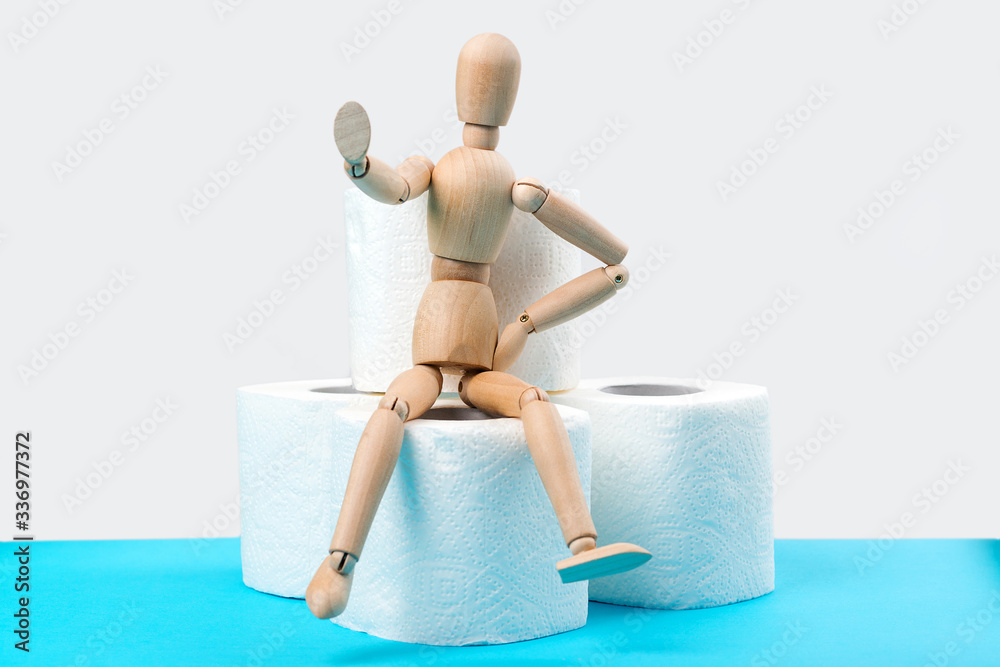 Stop panic. Wooden man sitting on a toilet paper rolls. Background with stock of toilet paper rolls. Stop panic. Wooden man sitting on a toilet paper rolls. Background with stock of toilet paper rolls.