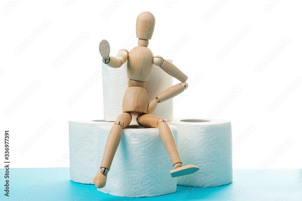Stop panic shopping during coranovirus outbreak. Wooden man sitting on a toilet paper roll. Coronavirus quarantine. Stop gesture. Stop panic shopping during coranovirus outbreak. Wooden man sitting on a toilet paper roll. Coronavirus quarantine. Stop gesture.
